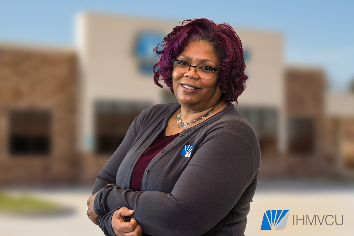 Black woman standing with arms crossed in front of blurred out building.