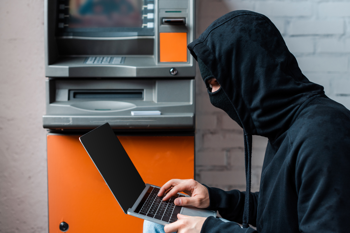 Man in black with laptop at ATM