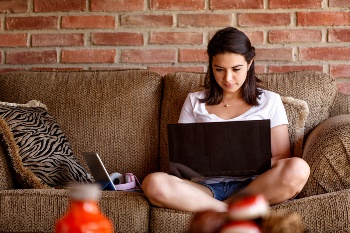 Girl sitting on her couch, on her computer