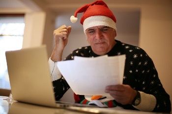 senior man working on budget in santa hat