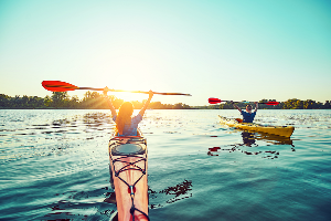 Two young people with arms up on kayaks