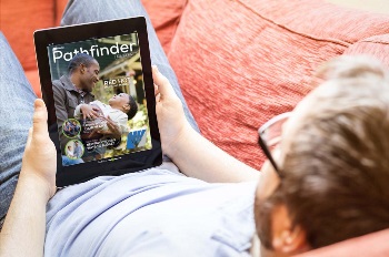 Guy laying on couch with tablet reading the magazine