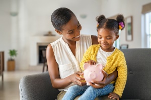 Mom holding daughter and piggy bank