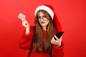 Woman holding credit card and phone looking angery