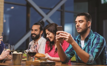 Three people sitting at a bar holding phone