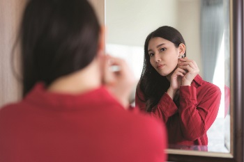 Asian women looking in the mirror while putting earrings on