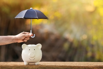 Piggy bank with someone holding a little umbrella over it