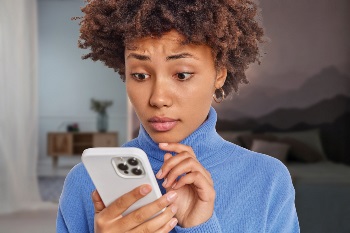 Woman with alarmed look on her face, looking at her phone