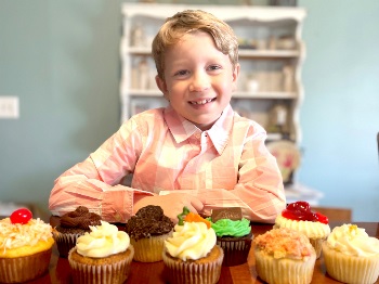 Sugar Daddy's Bakery owner, Raleigh, posing in front of his cupcakes