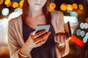 woman holding credit card and cell phone