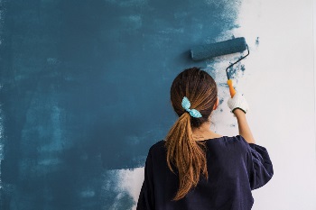 young woman painting wall blue